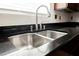 Close-up of a stainless steel kitchen sink with a modern faucet and black granite countertop at 6284 Pinewood Ave, Las Vegas, NV 89103