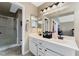 Bathroom with double sinks, white cabinets, vanity lighting, and separate glass shower at 629 Newbridge Way, North Las Vegas, NV 89032
