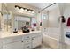 Bright bathroom featuring double sink vanity with white cabinets, tub, and large mirror at 629 Newbridge Way, North Las Vegas, NV 89032