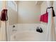 Close-up of a soaking tub with white tile surround and neutral colored walls and burgundy curtain ties at 629 Newbridge Way, North Las Vegas, NV 89032