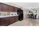 Open kitchen view with dark wood cabinets, black appliances, tile floors, and adjacent dining area at 629 Newbridge Way, North Las Vegas, NV 89032