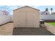 Tan storage shed with double doors in a backyard with gravel landscaping at 629 Newbridge Way, North Las Vegas, NV 89032