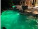 Beautiful backyard showcasing a freeform pool illuminated with green lights and poolside dining at 7685 Gilespie St, Las Vegas, NV 89123