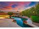 Scenic backyard pool with rock features, and vibrant landscaping, under a colorful sky at 7685 Gilespie St, Las Vegas, NV 89123