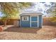 Backyard shed featuring blue wood construction, a window, and rock landscaping at 7685 Gilespie St, Las Vegas, NV 89123