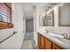 Bright bathroom featuring double sinks with wood cabinets and view to carpeted hallway at 8732 Majestic Pine Ave, Las Vegas, NV 89143