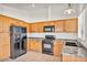 Well-lit kitchen with wood cabinets, granite countertops, and black appliances at 8732 Majestic Pine Ave, Las Vegas, NV 89143
