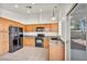 Bright kitchen with wood cabinets and black appliances, as well as outdoor access at 8732 Majestic Pine Ave, Las Vegas, NV 89143