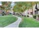 Well-manicured green space and sidewalk surrounded by garden-style condo buildings, shrubbery, and tall trees at 908 Domnus Ln # 203, Las Vegas, NV 89144