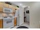 Cozy kitchen featuring wood cabinets, white appliances, and a separate nook with desk space at 908 Domnus Ln # 203, Las Vegas, NV 89144