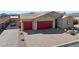 Wide exterior view of home with red garage doors, desert landscaping, and gated side yard at 91 Hawk Ave, Pahrump, NV 89060