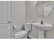 Bathroom featuring a modern toilet and pedestal sink, complemented by a round mirror at 9526 Vast Valley Ave, Las Vegas, NV 89148