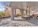 Spacious covered patio with ceiling fans, dining table, seating area, and lush landscaping at 9783 Hawk Crest St, Las Vegas, NV 89141
