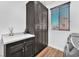 A well-organized laundry room featuring dark cabinets, a white countertop, and stylish wood-look tile flooring at 9783 Hawk Crest St, Las Vegas, NV 89141