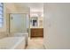 A bathroom with a bathtub, glass shower, wood cabinets, and a vanity mirror at 10632 Open Range Ct, Las Vegas, NV 89179