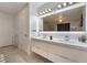 A modern bathroom with double sinks, sleek cabinetry, and a large mirror with modern lighting at 1168 Spago Ln, Henderson, NV 89052