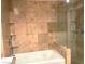 Bathroom with large bathtub, glass shower door, travertine tile and built in shower shelving at 30 Strada Di Villaggio # 118, Henderson, NV 89011