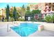 Inviting, small hot tub with blue tile decoratively lining the inside against lush, green shrubs and condo buildings at 30 Strada Di Villaggio # 118, Henderson, NV 89011