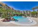 Large freeform swimming pool with rock features and towering palm trees near condominium buildings on a bright sunny day at 30 Strada Di Villaggio # 118, Henderson, NV 89011
