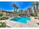 Resort-style pool featuring palm trees and pergola with a seating area near luxurious condo buildings on a bright sunny day at 30 Strada Di Villaggio # 118, Henderson, NV 89011