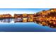Scenic waterfront view with illuminated buildings reflecting on the calm water at dusk at 30 Strada Di Villaggio # 118, Henderson, NV 89011