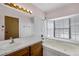 Bathroom featuring tile, a vanity, and a soaking tub beneath a window at 5070 Jeffreys St # 101, Las Vegas, NV 89119