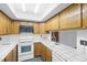 Well-lit kitchen with wood cabinetry, tiled countertops, and white appliances at 5070 Jeffreys St # 101, Las Vegas, NV 89119