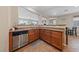 Open-concept kitchen with wood cabinets, stainless steel dishwasher, and view to dining area at 6030 Hidden Summit St, North Las Vegas, NV 89031