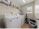 Bright laundry room with a white washer and dryer, wire shelving, and tile flooring at 6030 Hidden Summit St, North Las Vegas, NV 89031