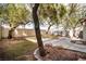 Inviting backyard with mature trees, a stone-lined garden bed, and a concrete patio at 8112 Broken Spur Ln, Las Vegas, NV 89131