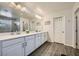 Primary bathroom with double sinks, wood-look floors, and a large mirror at 996 Cetona Ct, Henderson, NV 89011
