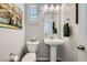 Stylish half bathroom featuring a pedestal sink, decorative mirror, and neutral wall color at 996 Cetona Ct, Henderson, NV 89011