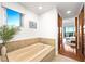Luxurious bathroom with a soaking tub, tile surround, and a window providing natural light and pleasant views at 11441 Allerton Park Dr # 212, Las Vegas, NV 89135