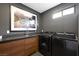 Well-equipped laundry room with modern washer and dryer, wooden cabinets, and countertop space, offering functionality at 2819 Queens Courtyard Dr, Las Vegas, NV 89109