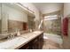 A well-lit bathroom with a marble countertop, dual sinks, a glass shower door, and tile walls at 2917 Chapala Dr, Las Vegas, NV 89120