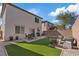 Well-maintained backyard featuring artificial grass, a patio area, and comfortable seating around a cozy fire pit at 460 Accelerando Way, Henderson, NV 89011