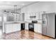 Open kitchen with stainless steel refrigerator, white cabinets, black appliances, and luxury vinyl plank flooring at 4837 Morning Splash Ave, Las Vegas, NV 89131