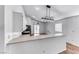 Bright kitchen with white cabinetry, bar counter, modern lighting fixture, and glass sliding doors to the backyard at 4837 Morning Splash Ave, Las Vegas, NV 89131