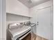 Well-lit laundry room featuring modern washer and dryer, storage shelf, and wood-look floors at 4837 Morning Splash Ave, Las Vegas, NV 89131