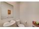 A clean half bathroom with white walls, a sink, and a toilet with a framed picture on the wall at 542 Foothill Cove Ln, Henderson, NV 89002