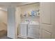 Bright laundry area features a full-size white washer, dryer, and ample storage space on the shelf at 542 Foothill Cove Ln, Henderson, NV 89002
