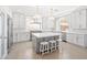 Bright kitchen features white cabinetry, an island, modern appliances, three barstools, and wooden floor at 6335 Mount Eden Ave, Las Vegas, NV 89139