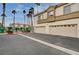 Exterior view of a two-story condo building with multi-car garage and palm trees in the landscaping at 6705 Squaw Mountain Dr # 102, Las Vegas, NV 89130