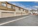 A long angle view of a condo complex featuring multiple garages and neutral color stucco at 6705 Squaw Mountain Dr # 102, Las Vegas, NV 89130