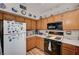 Well-lit kitchen with wood cabinets, black appliances, and neutral countertops at 6705 Squaw Mountain Dr # 102, Las Vegas, NV 89130