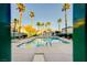A community pool with tall palm trees and lounge chairs near a clubhouse in the background at 6705 Squaw Mountain Dr # 102, Las Vegas, NV 89130