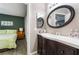 Bathroom with a wood vanity, oval mirror, and doorway view of a bedroom with green accent wall at 7950 W Flamingo Rd # 1037, Las Vegas, NV 89147