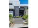 Modern home entrance featuring a black door, gray stone accents, decorative rock and lush plantings at 9 Boulderback Dr, Henderson, NV 89012