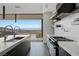 A modern kitchen with marble countertops, sleek black cabinets, and a stunning view of the surrounding landscape at 9 Boulderback Dr, Henderson, NV 89012