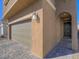 Inviting home exterior with a spacious two-car garage and textured walls and a quaint, arched doorway at 10279 Fragrant Apple Ct, Las Vegas, NV 89141